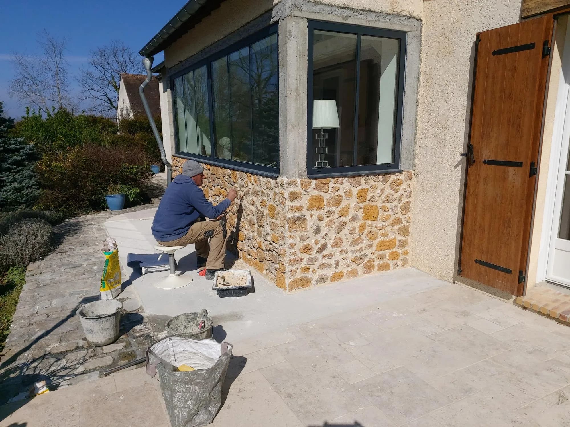 Maison ancienne rénovée mêlant soubassement en pierre apparente et grande baie aluminium