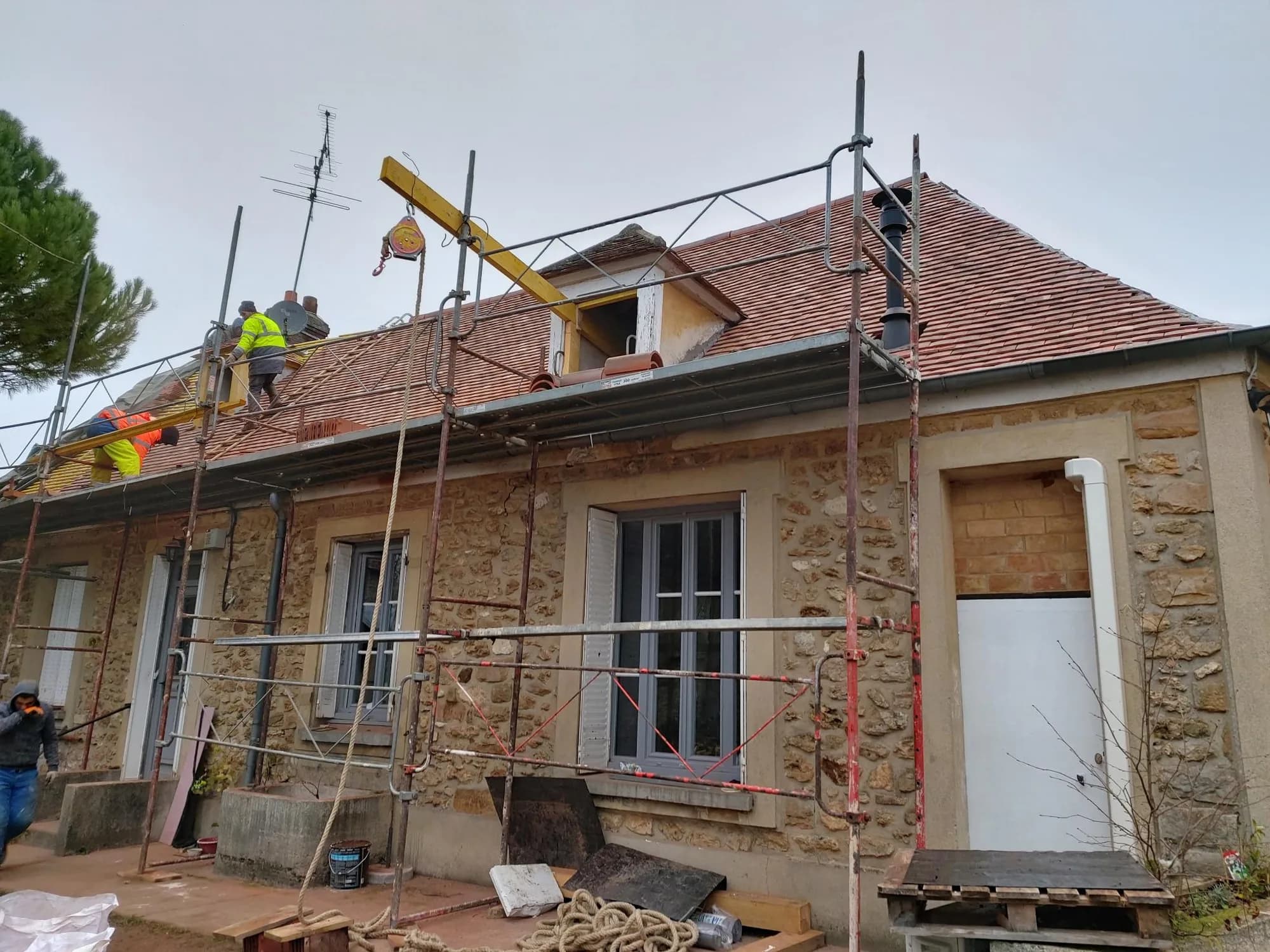Toiture de maison ancienne en réfection avec échafaudage et grue de chantier
