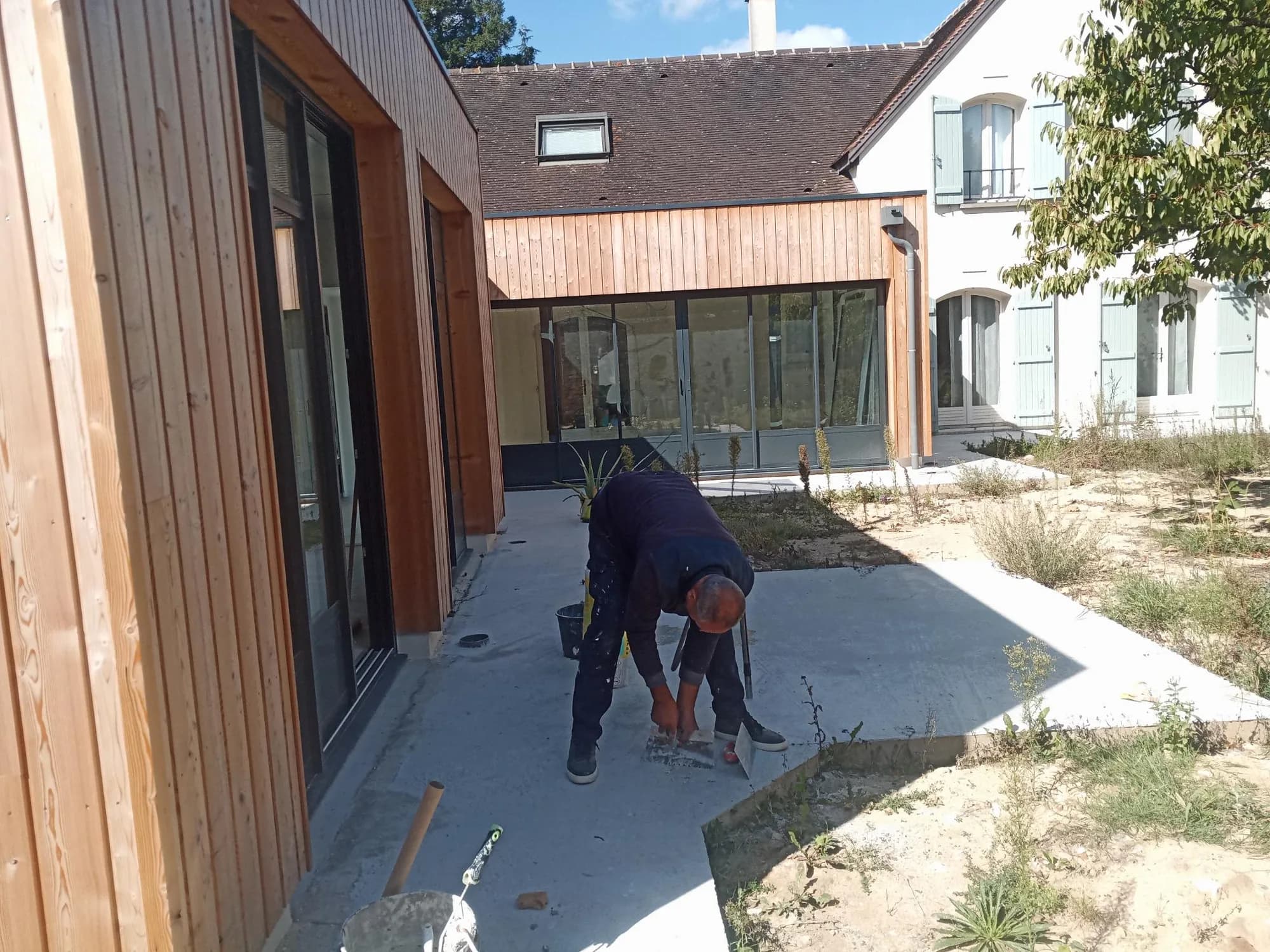 Extension en bardage bois donnant sur une cour intérieure, artisan au travail