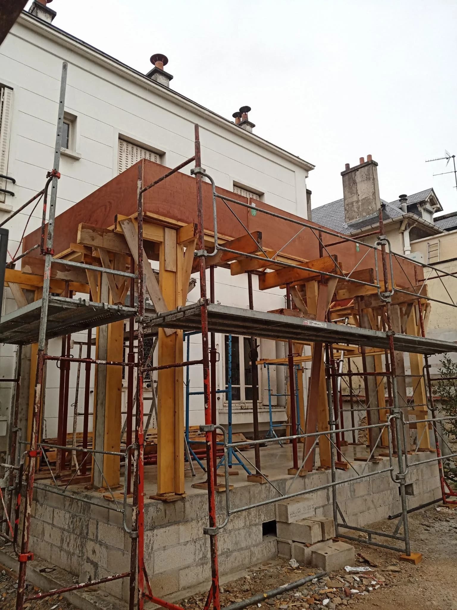 Bâtiment ancien étayé sous échafaudage bois pendant une reprise de structure